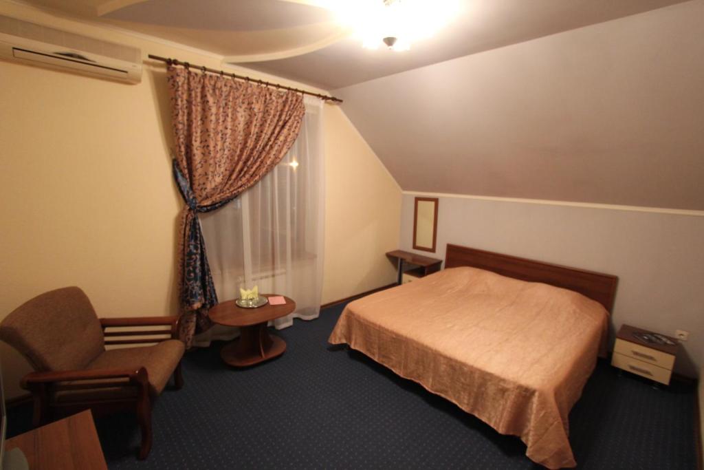 Habitación de hotel con cama, silla y ventana en Tis Hotel, en Krasnodar