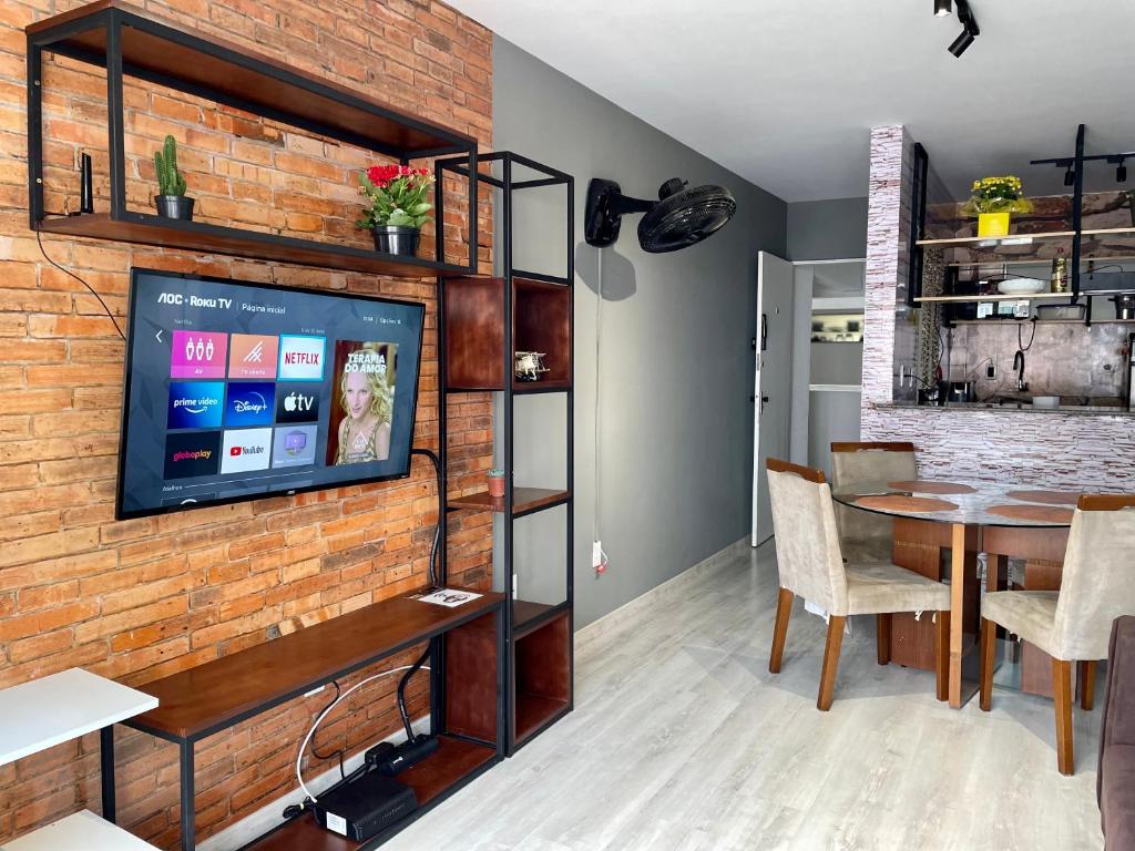 a dining room with a brick wall and a tv at DESCANSO FAMILIA PONTA VERDE in Maceió