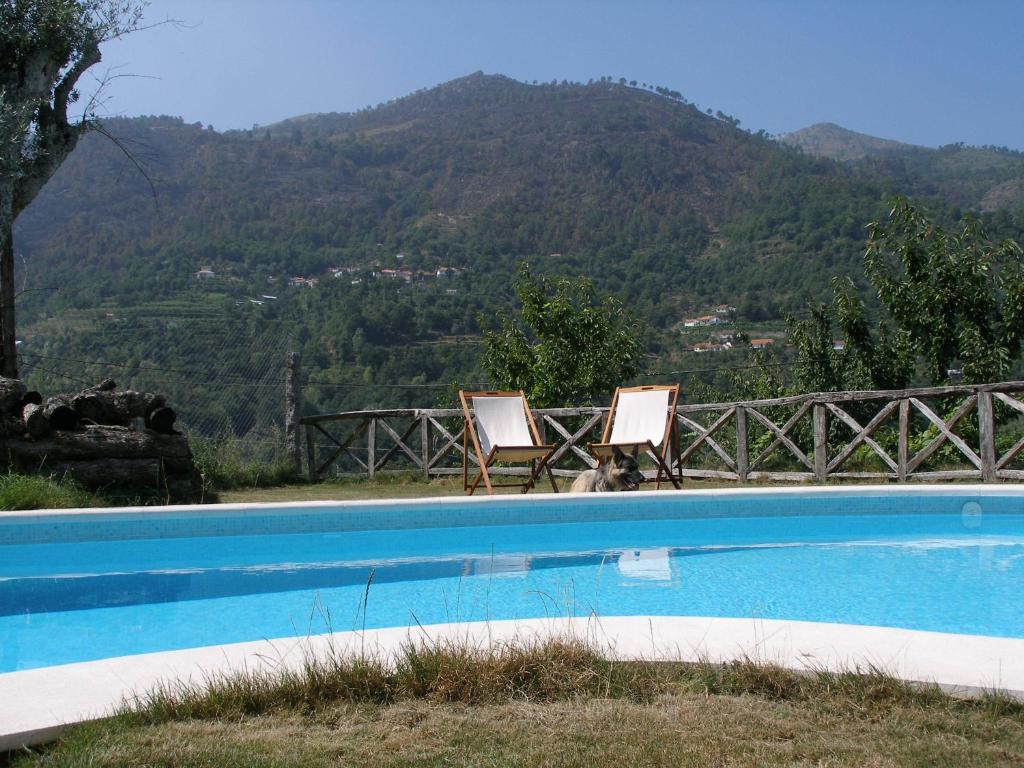 two chairs sitting next to a swimming pool with a mountain at Casa do Moleiro in Cinfães