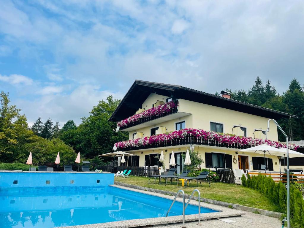 ein Haus mit Pool davor in der Unterkunft Pension Waldschenke am Wörthersee in Velden am Wörthersee