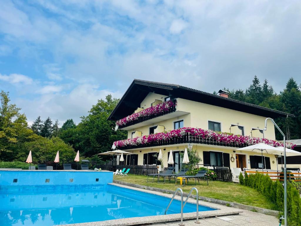 a house with a swimming pool in front of it at Pension Waldschenke am Wörthersee in Velden am Wörthersee