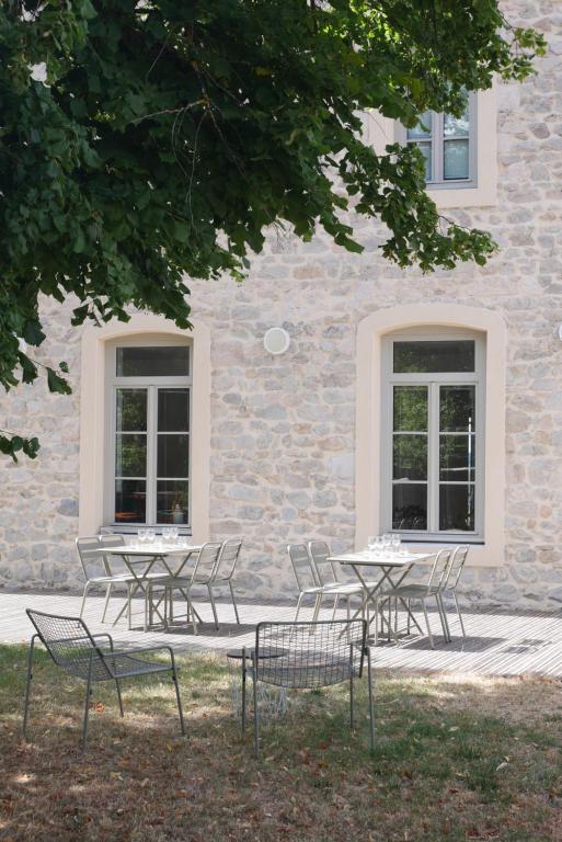 un grupo de mesas y sillas frente a un edificio en L'Auberge du Campos, en Saint-Pierre-Duchamp