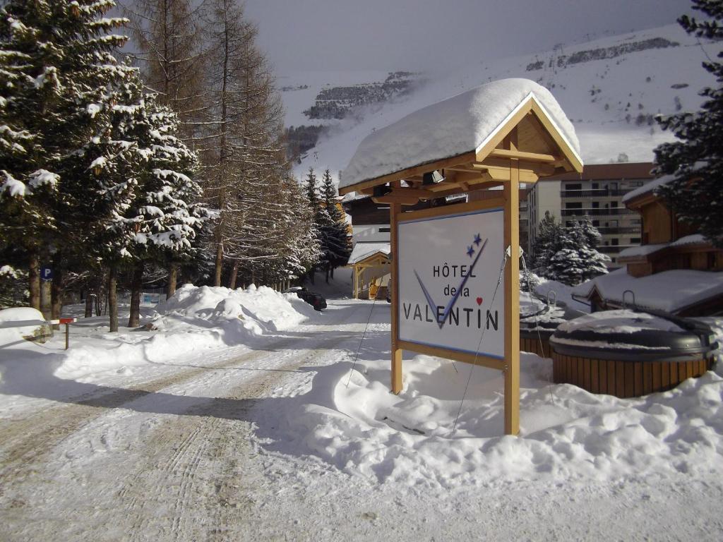 un cartel en la nieve frente a un edificio en Hôtel Valentin, en Les Deux Alpes