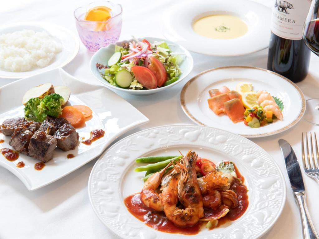 Una mesa blanca con platos de comida encima. en Tabist Sasebo Palace Hotel, en Sasebo
