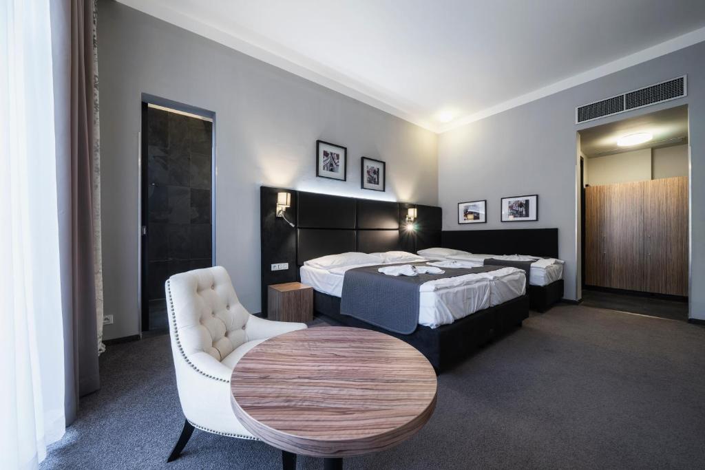 プラハにあるホテル ノワールのベッド2台とテーブルが備わるホテルルームです。