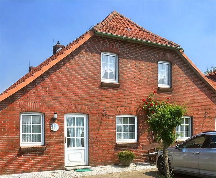 a red brick house with a car parked in front of it at Ferienwohnungen Haus Hasenweide in Stedesdorf