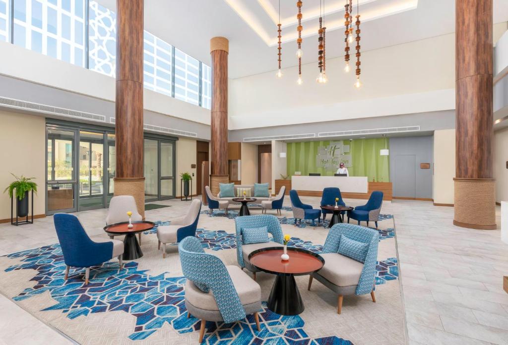 アル・ジュバイルにあるHoliday Inn & Suites Al Jubail, an IHG Hotelの青い椅子とテーブルが備わるロビー