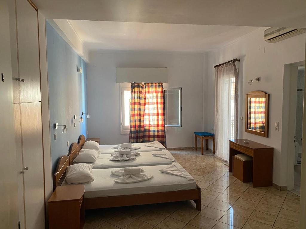 Habitación blanca con cama y ventana en Hotel Damo en Pythagóreion