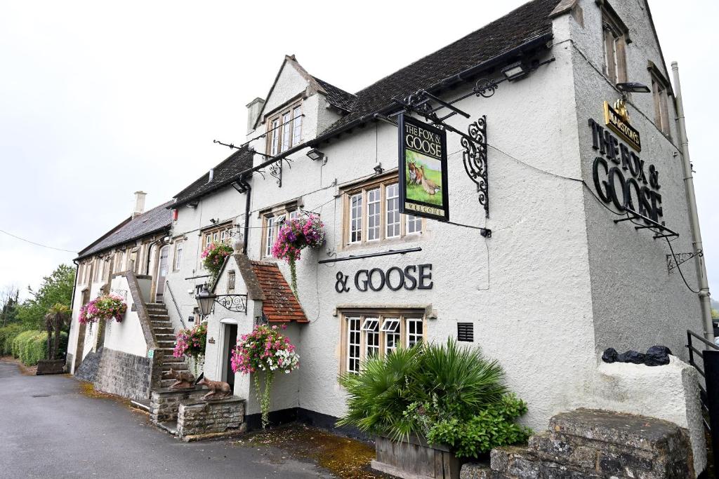 Un bâtiment blanc avec un panneau indiquant café et oie dans l'établissement Fox & Goose, Barrow Gurney by Marston's Inns, à Bristol