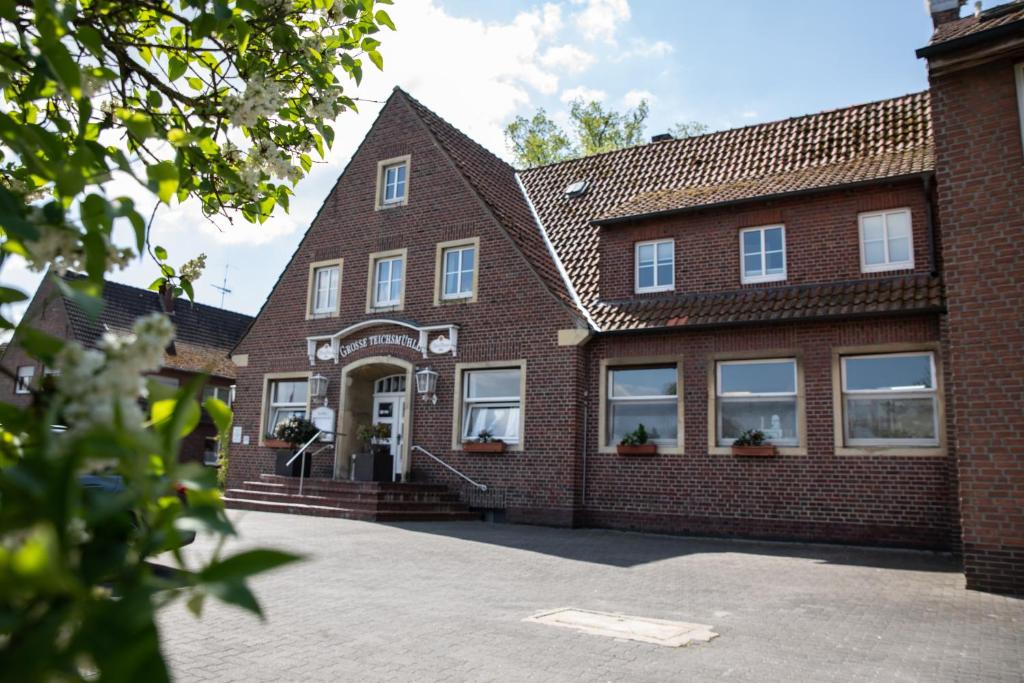 a brick building with windows and a driveway at Hotel Restaurant Große Teichsmühle in Dülmen
