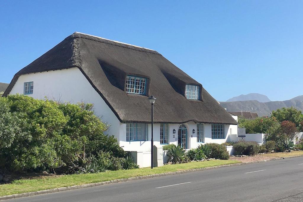 a thatch roofed house on the side of the road at Cliff Cottage Hermanus in Hermanus