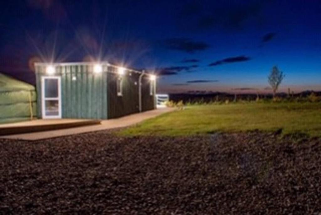 un pequeño edificio verde con luces encendidas por la noche en Colourful Mongolian Yurt enjoy a new experience, en Turriff