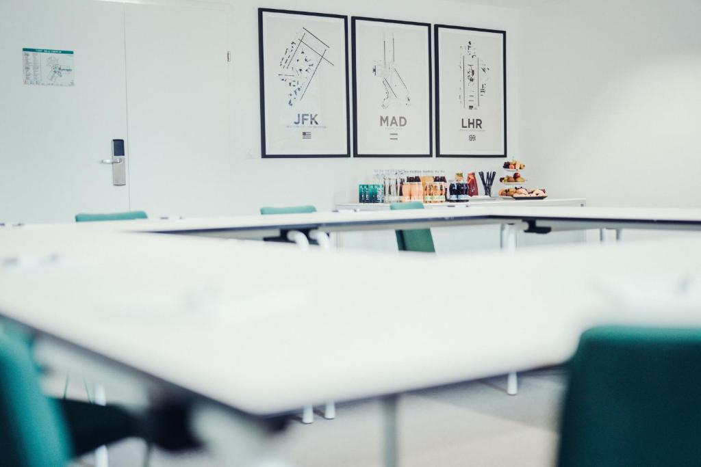 a classroom with white tables and drawings on the wall at Airbase Hotel in Kalsdorf bei Graz
