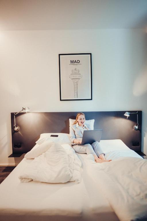 a woman laying on a bed with a laptop at Airbase Hotel in Kalsdorf bei Graz