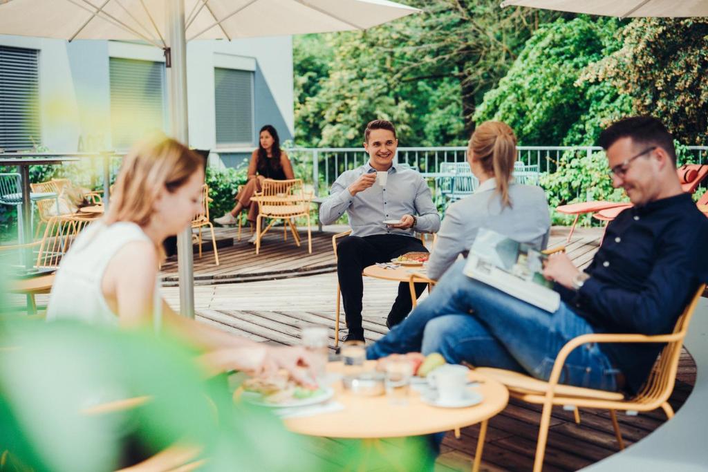 a group of people sitting at tables on a patio at Airbase Hotel in Kalsdorf bei Graz