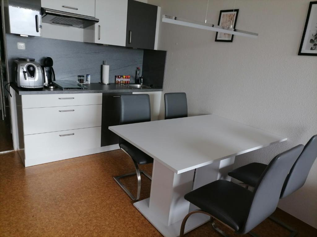 2-Raum Appartement Saxo في سانكت انجلمار: مطبخ صغير مع طاولة بيضاء وكراسي