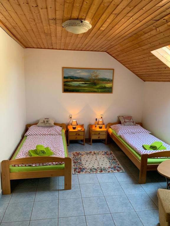 a room with two beds and a wooden ceiling at Penzión Farmárik in Bolešov