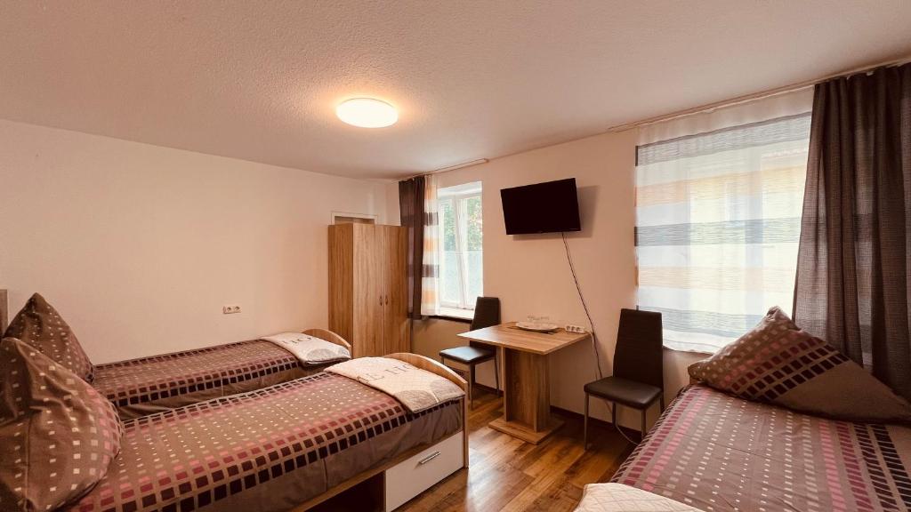 una camera d'albergo con due letti e una televisione di Sehr zentrales und modernes Zimmer in Isny im Allgäu mit Gemeinschaftsbad a Isny im Allgäu