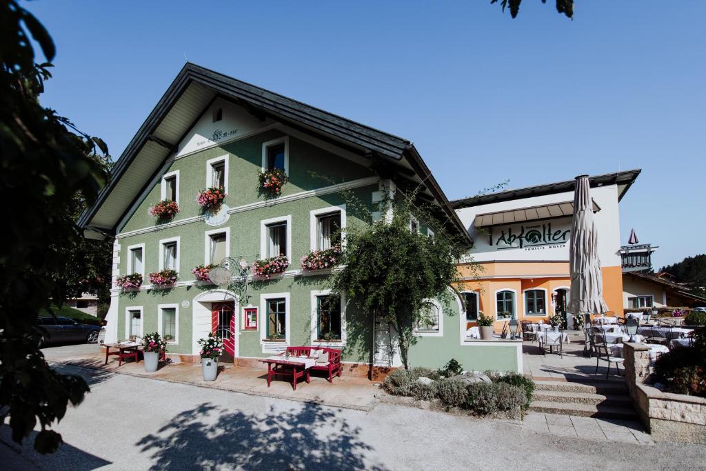 a green building with tables and benches in front of it at Gasthof Abfalter in Golling an der Salzach