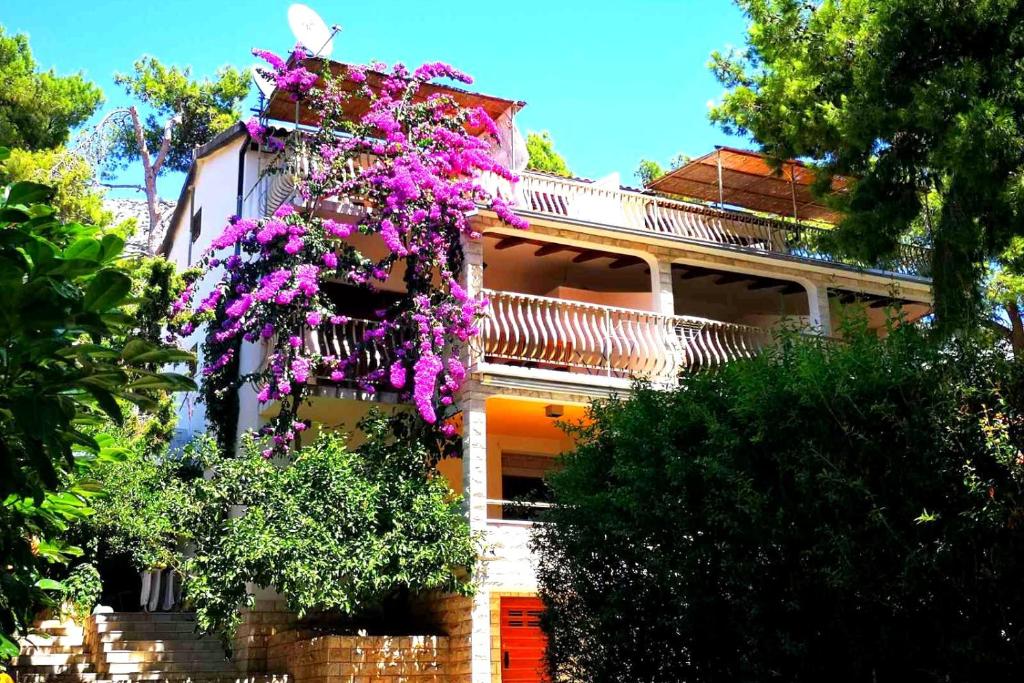 une maison avec des fleurs violettes sur son côté dans l'établissement Apartments by the sea Ivan Dolac, Hvar - 8700, à Jelsa