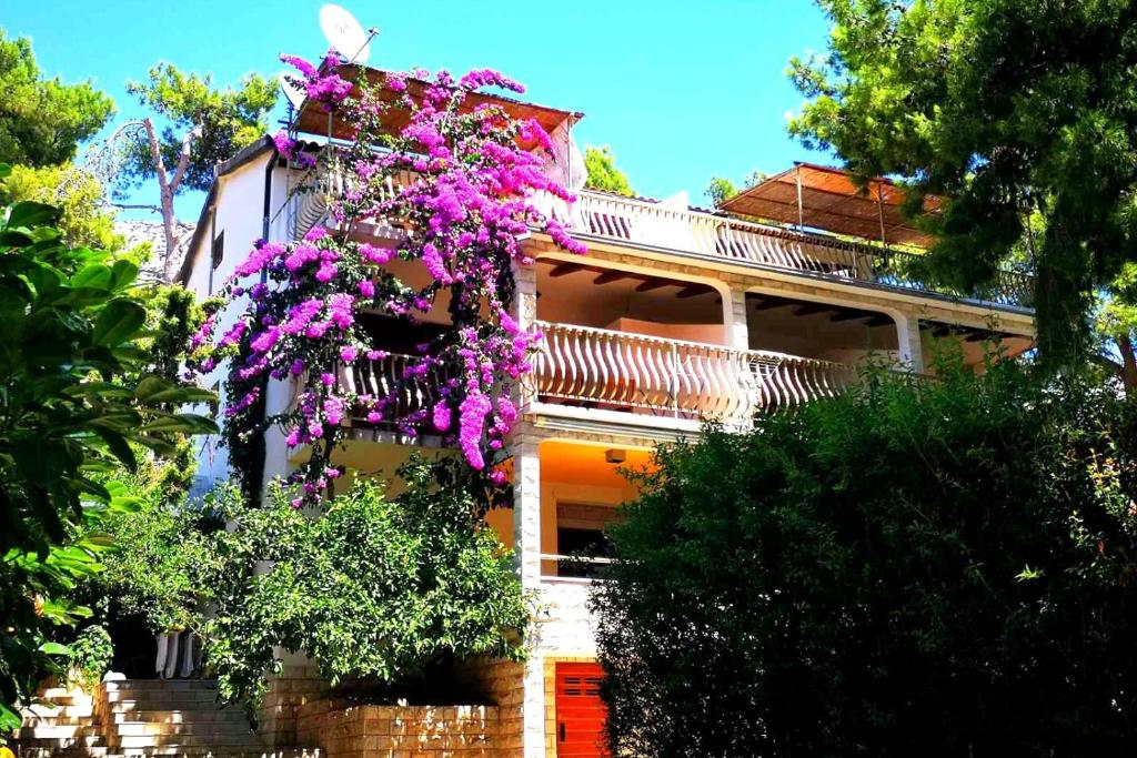 ein Haus mit lila Blumen an der Seite in der Unterkunft Apartments by the sea Ivan Dolac, Hvar - 8700 in Jelsa