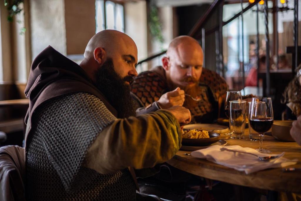 a group of men sitting at a table eating food at Peanut Medieval Lodge in Saint-Ursanne