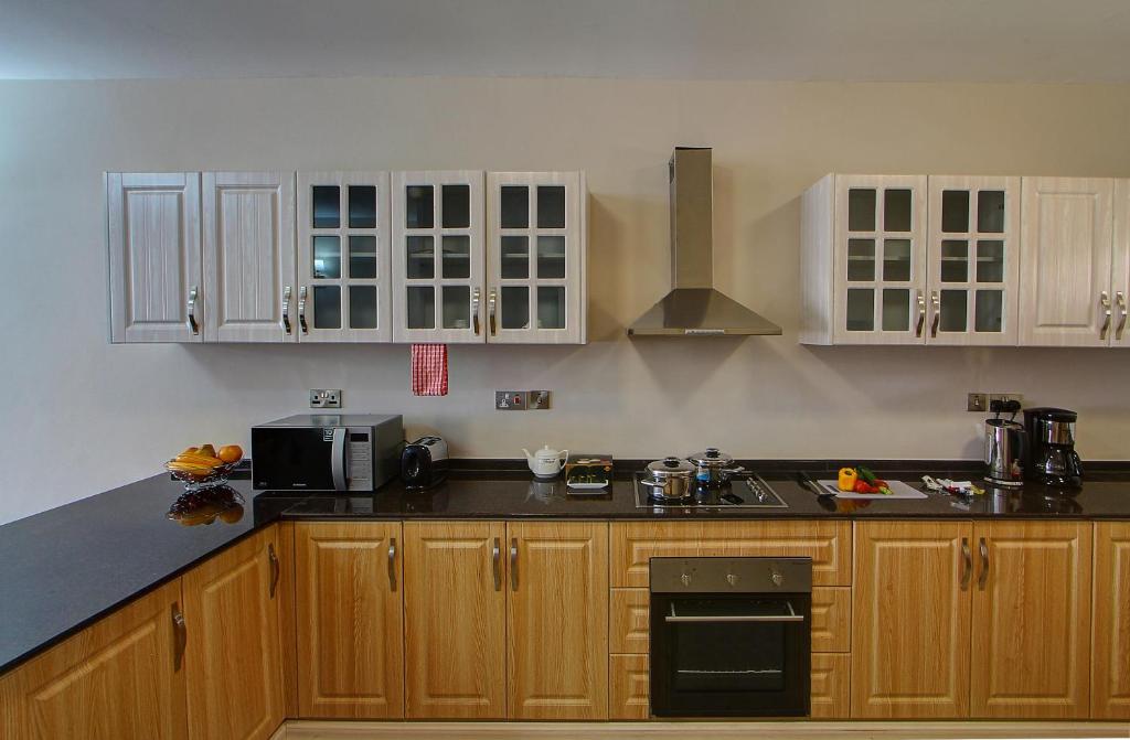 una cucina con armadi in legno e piano di lavoro nero di Fenesi Gardens Apartments a Nairobi