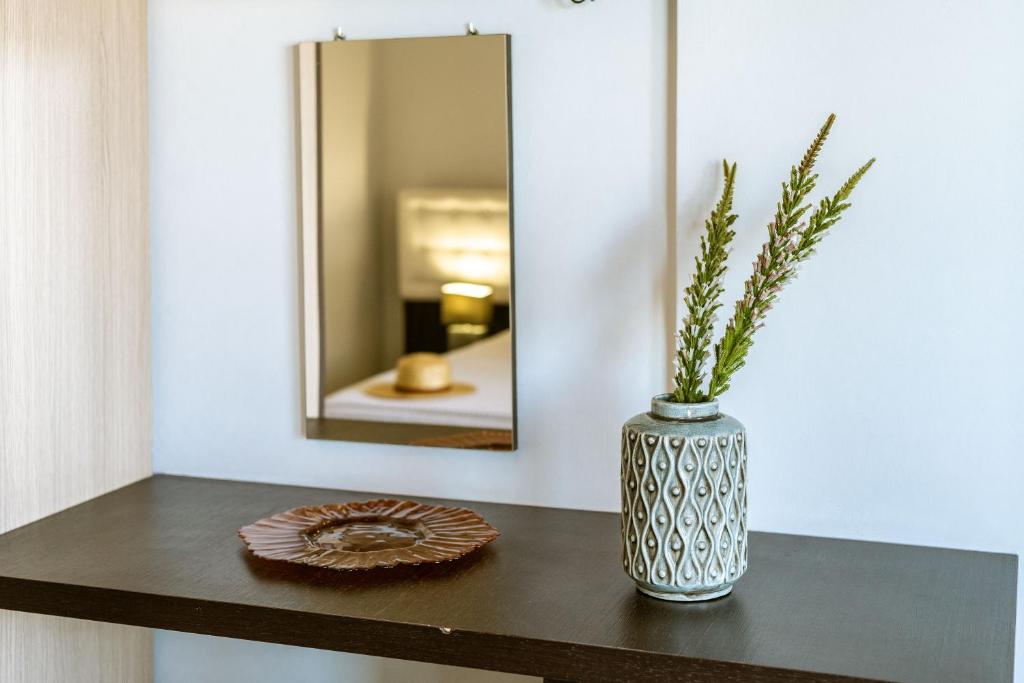 a vase on a table with a plate and a mirror at 3Aktes Suites & Studios in Syvota