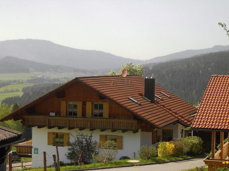 ein Haus mit einem Dach mit Bergen im Hintergrund in der Unterkunft Familienferienhof Kroner in Zwiesel