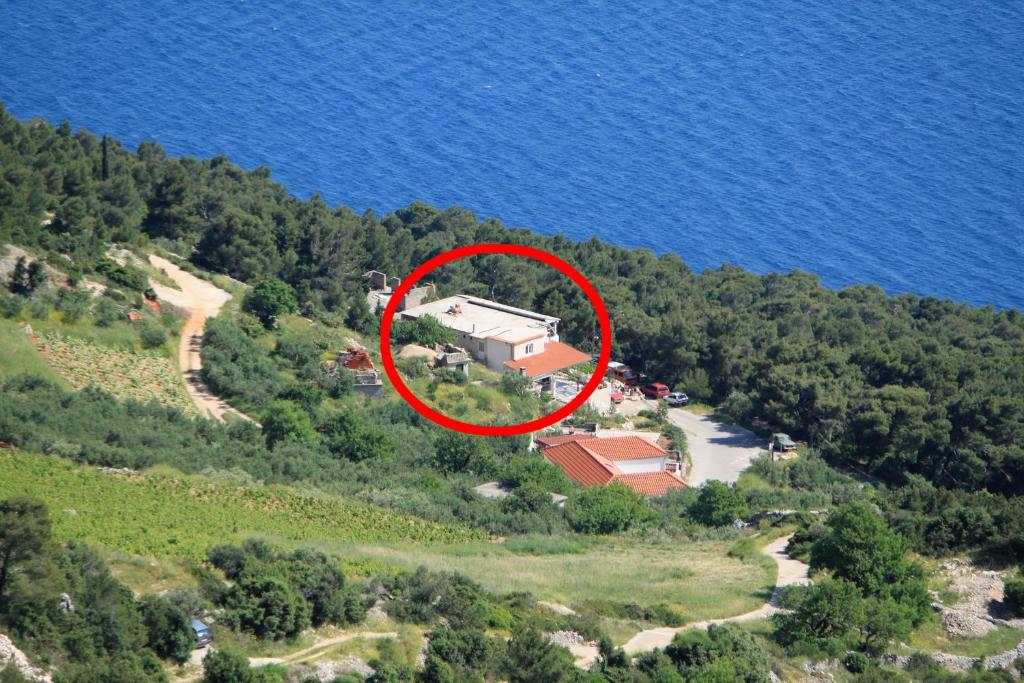 a house on a hill near the water with a red circle at Apartments with a parking space Sveta Nedilja, Hvar - 8792 in Sveta Nedelja