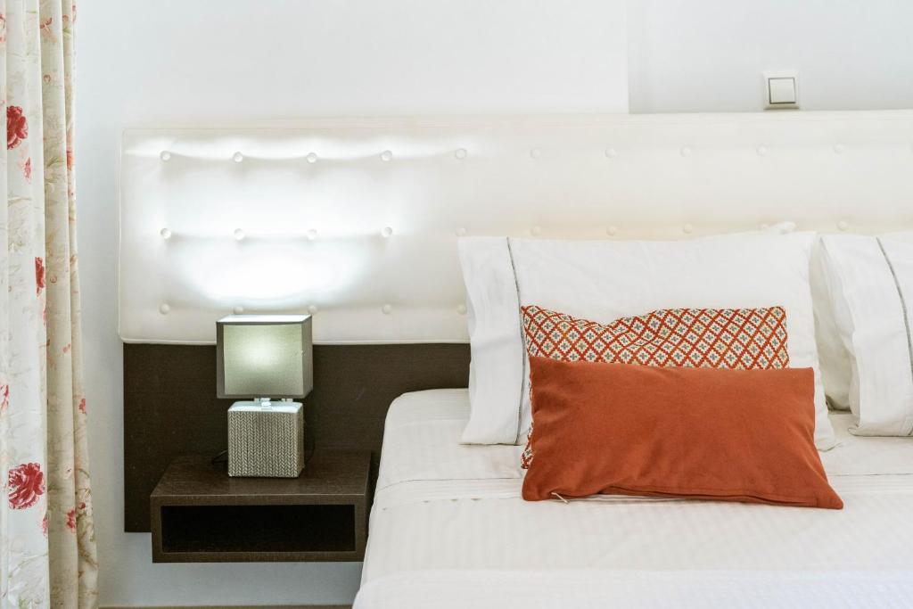 a bedroom with a white bed with an orange pillow at 3Aktes Suites & Studios in Syvota