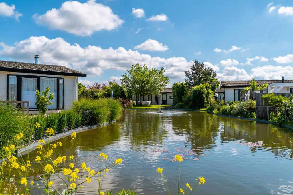 einen Garten mit einem Teich vor einem Haus in der Unterkunft EuroParcs de Woudhoeve in Egmond aan den Hoef