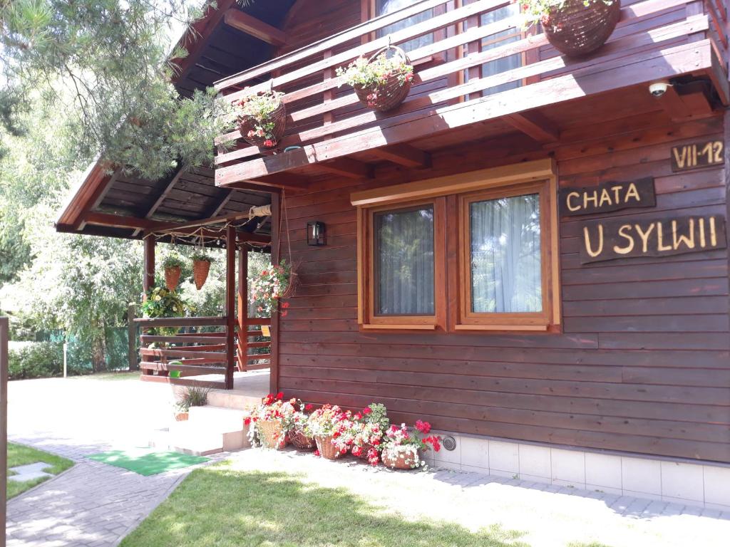 a wooden house with flowers in front of it at Chata u Sylwii in Okuninka