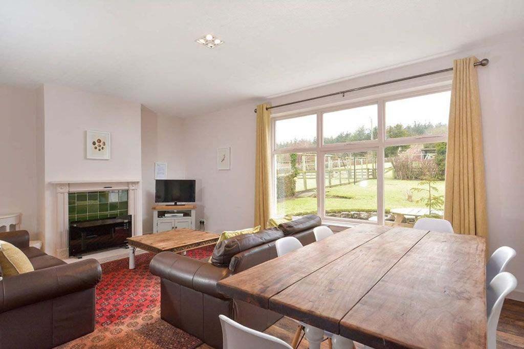 uma sala de estar com uma mesa de madeira e uma grande janela em Kittocks Muir em St. Andrews