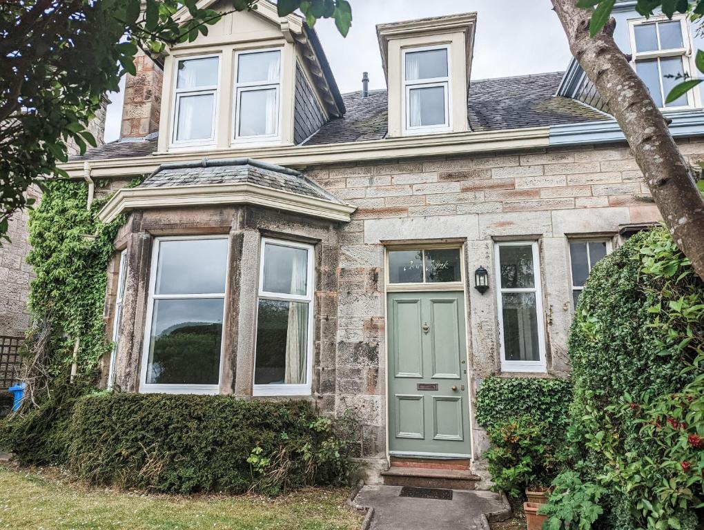 una casa de ladrillo con una puerta verde en Rosebank en St Andrews