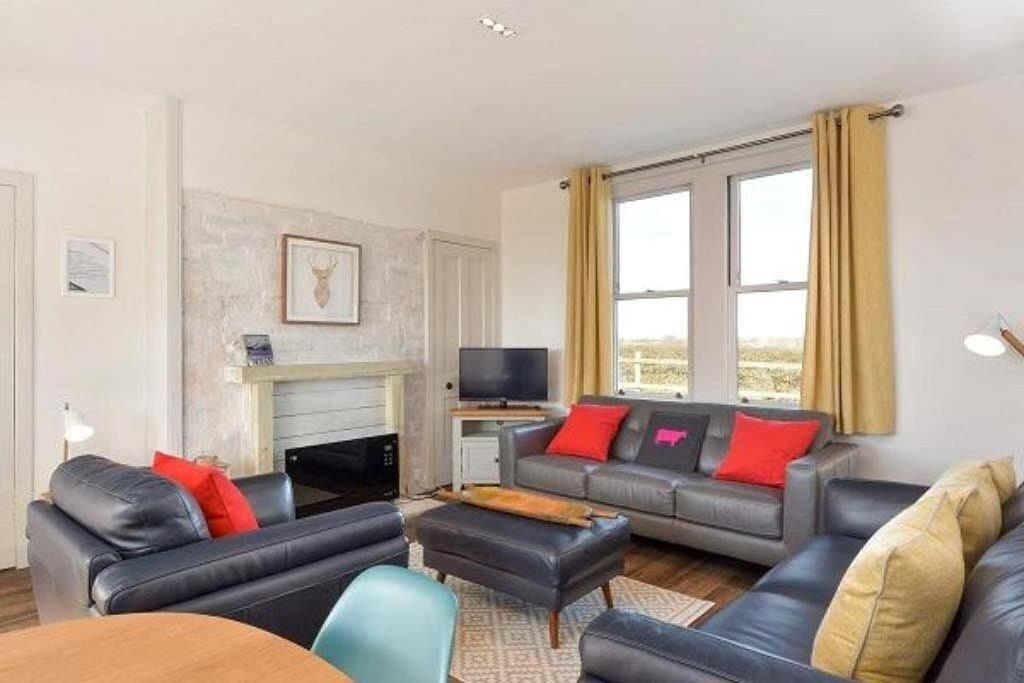 uma sala de estar com sofás de couro e uma televisão em Mick's Cottage em Crail