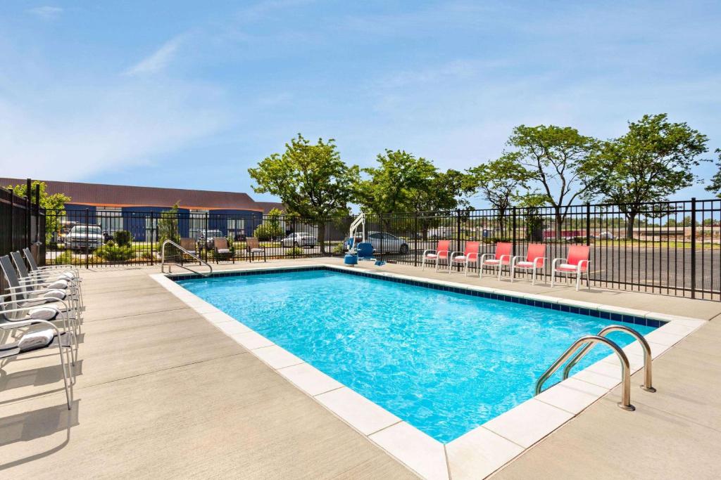 a swimming pool with chairs and a fence at Super 8 by Wyndham Lenexa Overland Park Area/Mall Area in Lenexa