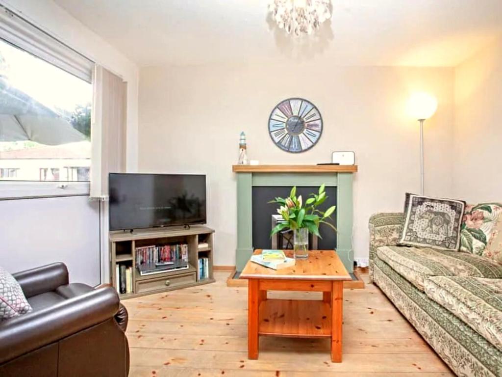 a living room with a couch and a table and a tv at Dawlish Warren Holidays in Dawlish