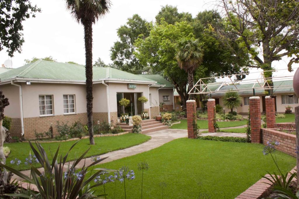 a house with a lawn and palm trees at Hotel Mount Maluti - Lesotho in Mohales Hoek