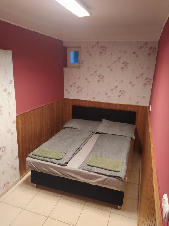 a bed in a room with a red wall at Pingpong Apartman in Soltvadkert