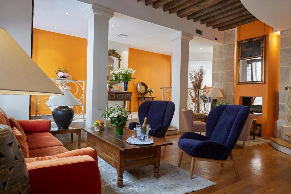 a living room with orange walls and blue chairs at Le Clos Medicis in Paris