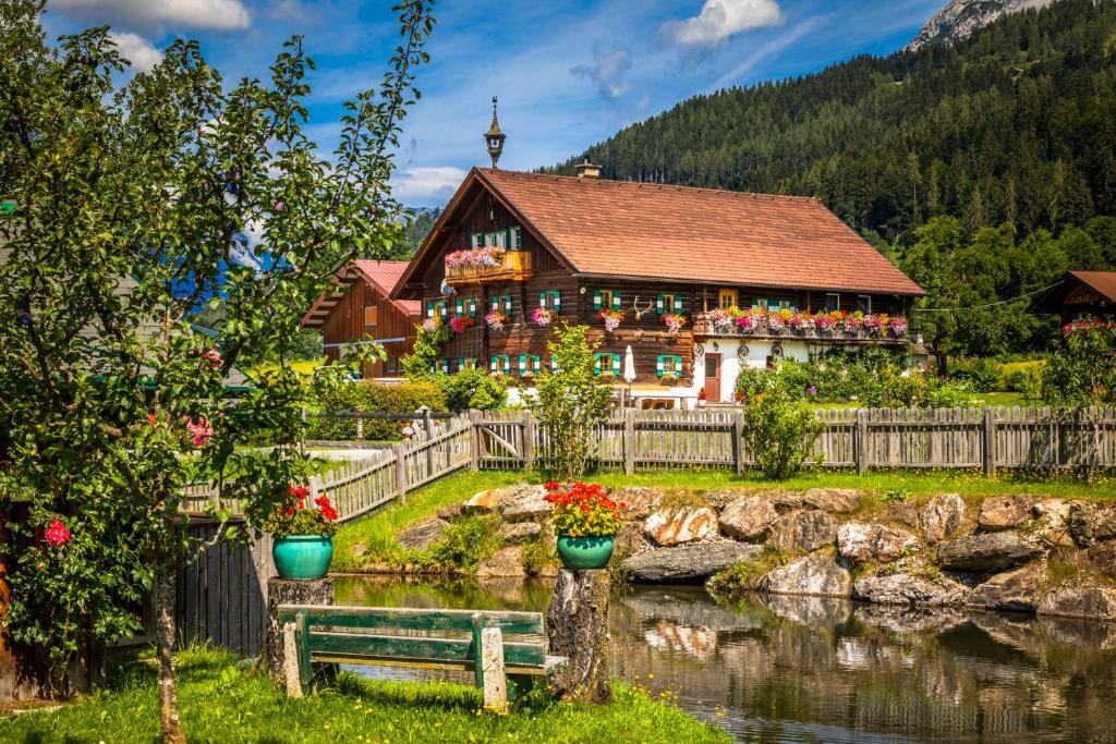 a house with flowers in front of a lake at Bauernhof Lehengut in Pfarrwerfen