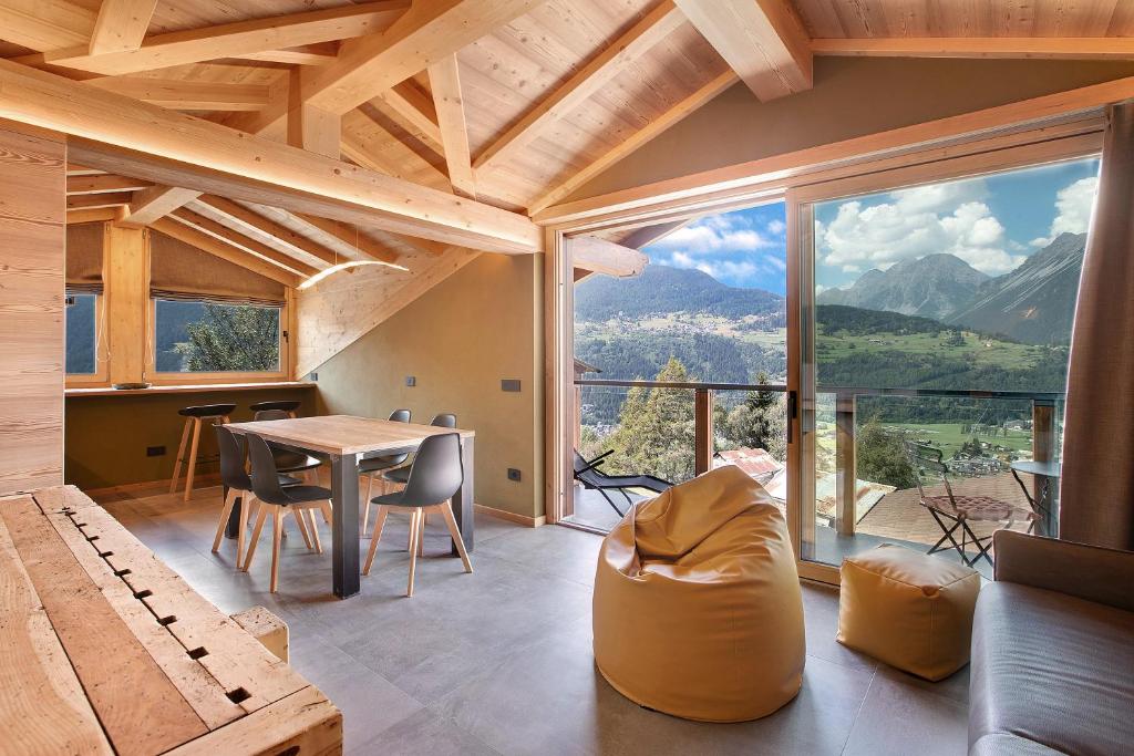 Habitación con mesa, sillas y ventana grande. en Aria di Casa Piazzi, en Valdisotto