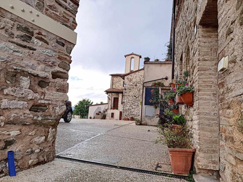 eine Gasse mit einem alten Steingebäude und einer Kirche in der Unterkunft Ospitaci Appartamenti Giove in Valtopina