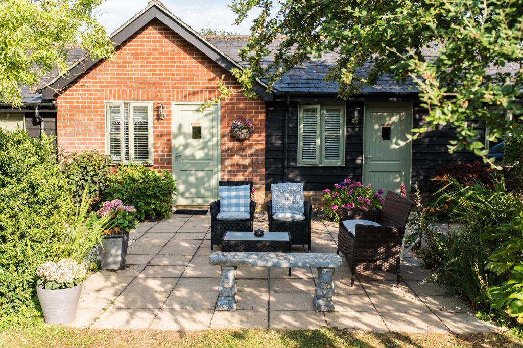 a patio with two chairs and a bench in front of a house at The Foxes Den in Assington