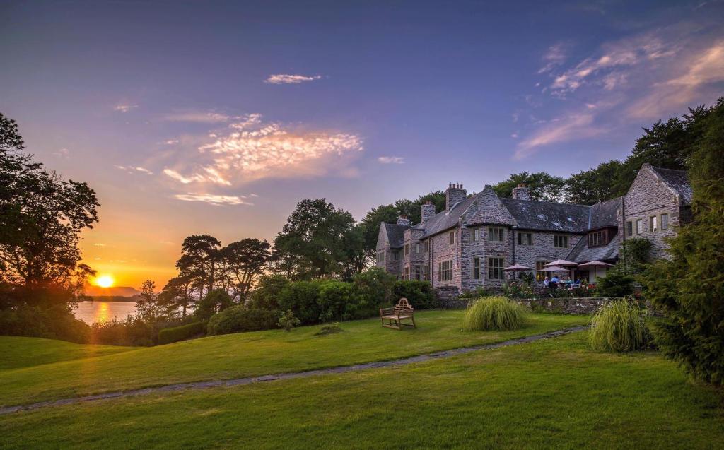 a large house on a lawn with the sunset in the background at Ard na Sidhe Country House Hotel in Killorglin