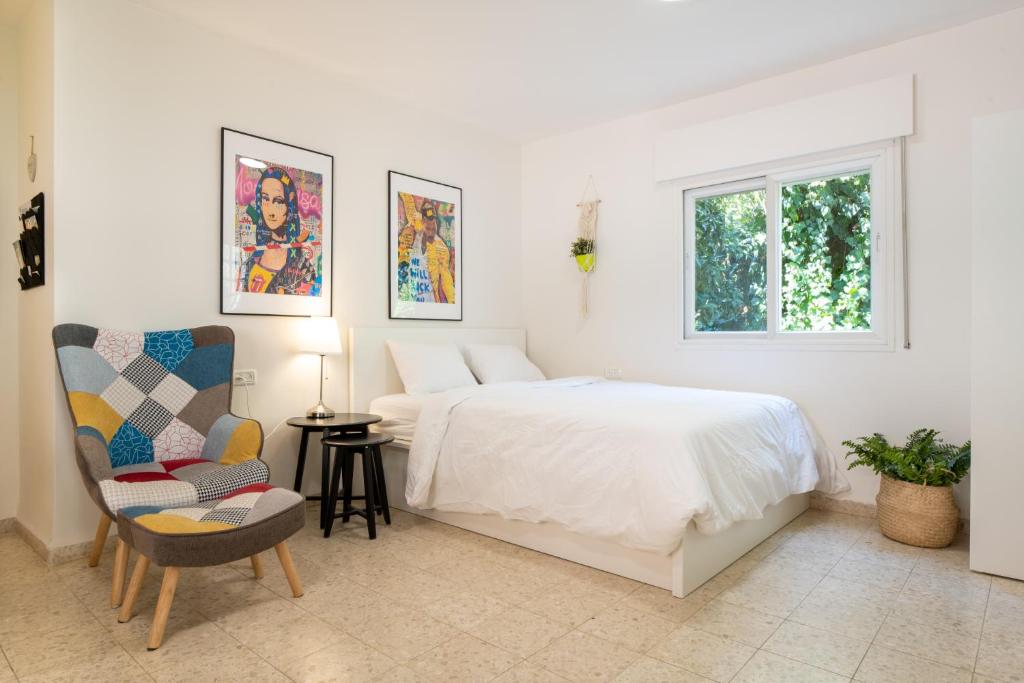 1 dormitorio blanco con 1 cama y 1 silla en ירוק באלה - דירת נופש ברמת ישי en Ramat Yishay