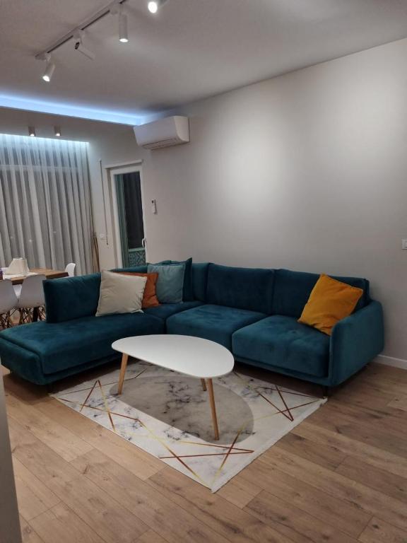 a living room with a blue couch and a white table at Star Apartament Gjiri lalzit, Lura 2 in Lalzit Bay