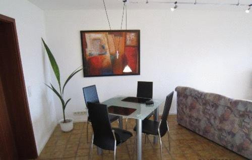 stół jadalny z krzesłami i obraz na ścianie w obiekcie Ferienwohnung Erika w mieście Grenzach-Wyhlen