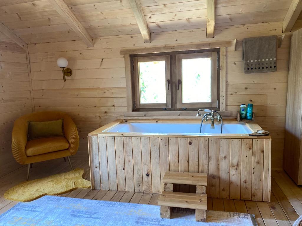 ウルツィニにあるPeaceful Oasisの椅子付きの客室内に大きな木製バスタブがあります。